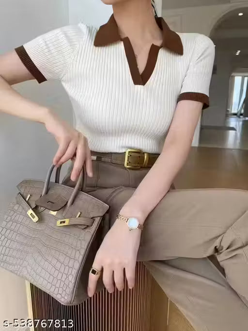 Person wearing a white and brown polo shirt with beige pants, holding a handbag.